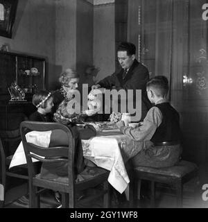 Eine Familie sitzt im Wohnzimmer am Kaffeetisch, Deutschland 1930er Jahre. Une famille assise au tabele, ayant un café, Allemagne des années 1930. Banque D'Images