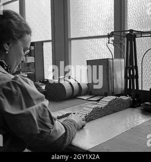 Arbeitsalltag in der Zigarettenfabrik, hier beim Zigarettenrollen, Deutschland 1930er Jahre. Journée de travail dans une usine de cigarettes, ici: Femme roulant des cigarettes, Allemagne des années 1930. Banque D'Images