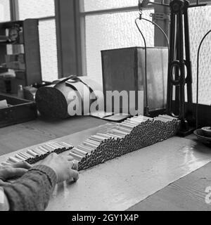 Arbeitsalltag in der Zigarettenfabrik, hier beim Zigarettenrollen, Deutschland 1930er Jahre. Journée de travail dans une usine de cigarettes, ici: Femme roulant des cigarettes, Allemagne des années 1930. Banque D'Images