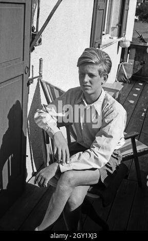 Ein junger Mann sitzt dans der sonne, Deutschland 1940er Jahre. Jeune homme relaxant au soleil, Allemagne des années 1940. Banque D'Images