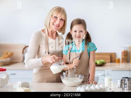Bonne dame âgée et sa petite-fille pétrir la pâte, posant Banque D'Images