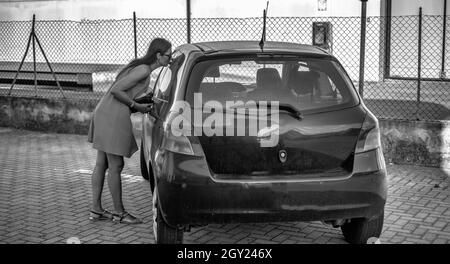 Belle femme embrasse sa vieille voiture, achète une nouvelle voiture Banque D'Images