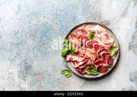 Hors-d'œuvre avec différents antipasti, charcuterie, encas et vin rouge. Saucisses, jambon, tapas, olives et craquelins pour la fête sous forme de buffet. Vue de dessus, plan d'appartement Banque D'Images