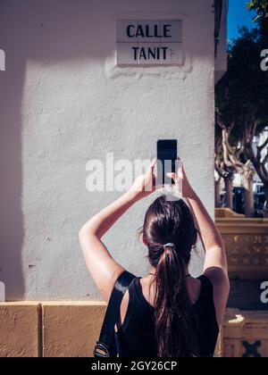 Femme prenant la photo d'un panneau de rue sur un mur de son smartphone Banque D'Images
