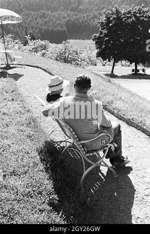 Ein junges Paar entspannt bei der Zeitschriftenlektüre im Garten, Freudenstadt, Deutschland 1930 er Jahre. Un couple avec un magazine dans le jardin, Freudenstadt, Allemagne 1930. Banque D'Images