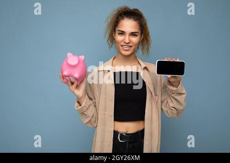 Photo de jeune insatisfait douteux belle brune belle femme avec des émotions sincères portant élégante chemise beige isolée sur bleu Banque D'Images