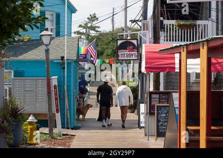 Couple gay marchant le long de la promenade à travers le quartier central des affaires (ville) de Cherry Grove sur Fire Island, New York, comté de Suffolk, États-Unis. Banque D'Images