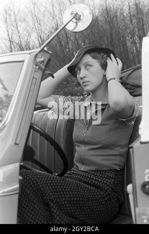 Eine junge Frau schminkt sich im Seitenspiegel votre Cabrios, Deutschland 1930er Jahre. Une jeune femme contrôler son faire dans le miroir de l'aile de son cabriolet, Allemagne 1930. Banque D'Images