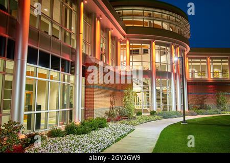 Trottoir menant à la porte d'entrée d'un dortoir avec beaucoup de fenêtres la nuit Banque D'Images