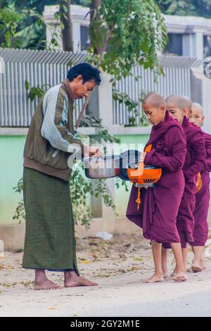 BAGAN, MYANMAR - 8 DÉCEMBRE 2016: Rangée de jeunes moines bouddhistes avec des bols collectant leurs almes quotidiens. Banque D'Images