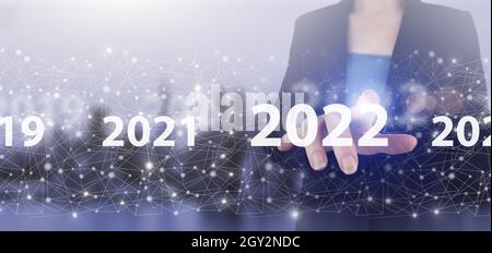 Chargement des années 2021 à 2022.Démarrer le concept.Écran numérique tactile main hologramme 2022 signe sur la ville lumière arrière-plan flou.Nouvel an 2022,objectif,plan,actif Banque D'Images