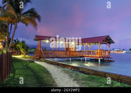 Jetée pour passagers sur l'île de Carenero, à droite acros de Bocas ville dans la province de Bocas del Toro de Panama sous une belle lumière pourpre coucher de soleil. Banque D'Images