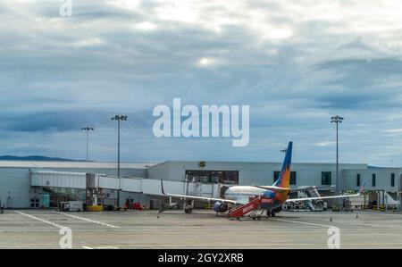 Un Boeing 737-800 dans la décoration de Jet2 debout sur un tablier à l'aéroport de Glasgow, en Écosse.Un pont à jet est fixé. Banque D'Images