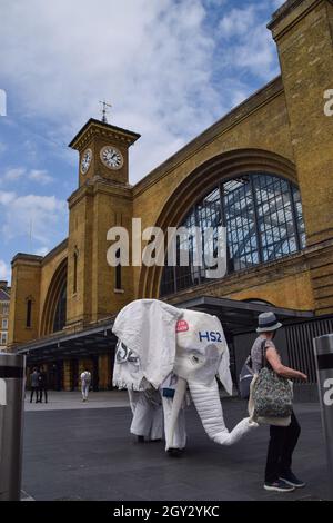 Londres, Royaume-Uni.5 août 2021.Les manifestants portant un costume d'éléphant blanc « HS2 » sont conduits à l'extérieur de la gare par un autre manifestant.Des militants se sont rassemblés devant la gare de King's Cross pour protester contre le nouveau système ferroviaire High Speed 2 (HS2), qui selon les écologistes sera « écologiquement dévastateur » et coûtera aux contribuables 170 milliards de livres sterling. Banque D'Images