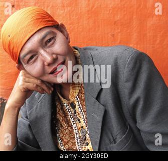 Une femme portant un foulard orange ou hijab et un blazer gris vendant des piments rouges sur un marché extérieur à Bukittinggi, Sumatra Ouest, Indonésie. Banque D'Images