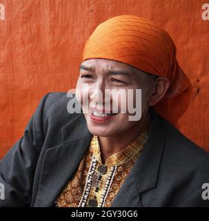 Une femme portant un foulard orange ou hijab et un blazer gris vendant des piments rouges sur un marché extérieur à Bukittinggi, Sumatra Ouest, Indonésie. Banque D'Images
