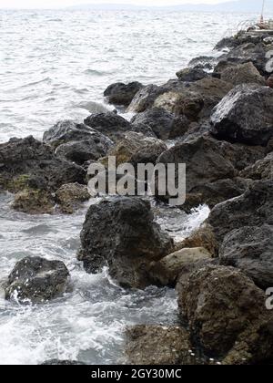 Les vagues se brisent sur des rochers à Anemomylos, dans la baie de Garitsa, à Corfou, en Grèce Banque D'Images