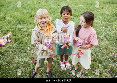 Portrait complet de trois enfants adorables tenant des bonbons de la pinata pendant la fête d'anniversaire à l'extérieur Banque D'Images