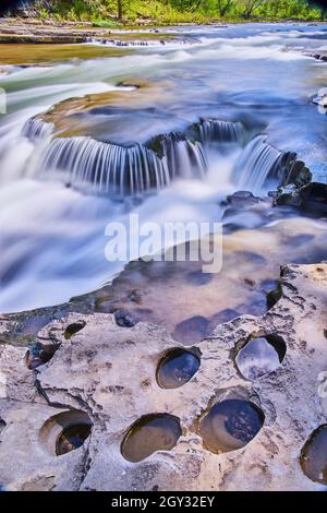 Côte rocheuse avec de petits trous à côté de petites cascades Banque D'Images