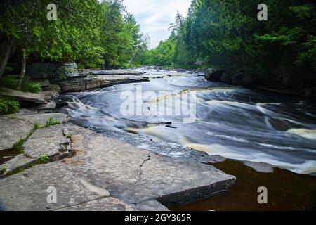 Vue sur la rivière avec petites cascades le long de rochers gris Banque D'Images