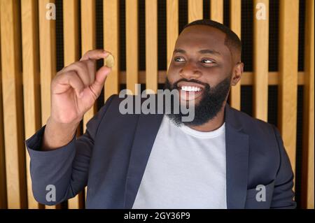 Un homme barbu à la peau sombre tenant un bitcoin Banque D'Images