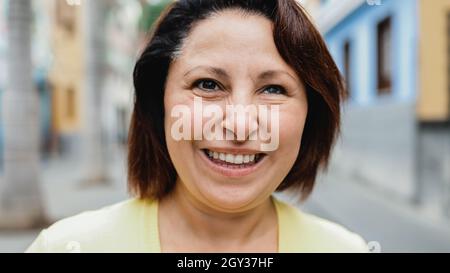Portrait d'une femme mûre souriant sur l'appareil photo en plein air dans la ville - concept de personnes réelles Banque D'Images