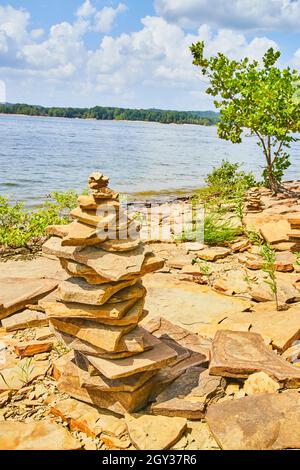 Pile de pierres (cairn) sur une plage chaude avec des rochers Banque D'Images