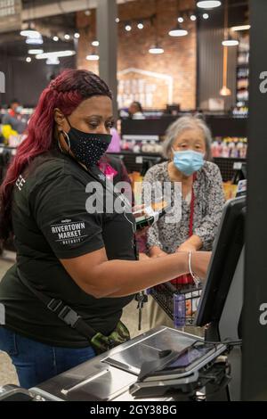 Detroit, Michigan - Rivertown Market, un supermarché plus petit exploité par la chaîne Meijer, est ouvert dans le centre-ville de Detroit.Un travailleur aide un acheteur Banque D'Images