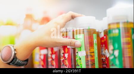 WUHAN, CHINE- SEP 22, 2021: Main de femme en gros plan en choisissant le thé vert qui est prêt à boire sur l'étagère au supermarché local. Banque D'Images