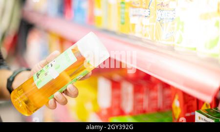 WUHAN, CHINE- SEP 22, 2021: Main de femme en gros plan en choisissant le thé vert qui est prêt à boire sur l'étagère au supermarché local. Banque D'Images