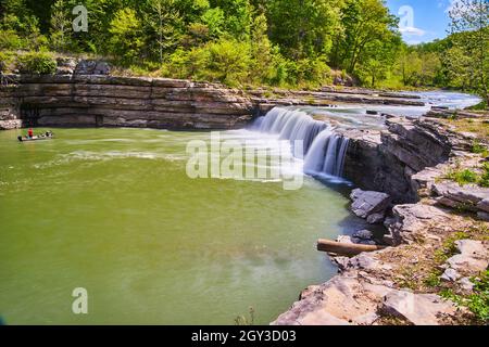 Pêcheur en bateau dans la gorge à côté de la grande cascade dans la forêt Banque D'Images