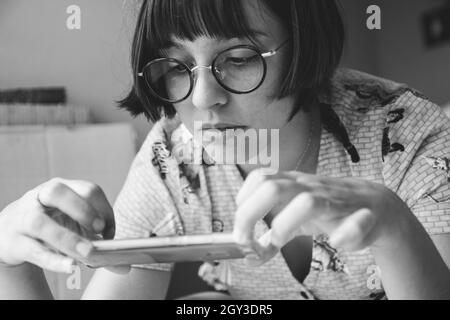 Photo en niveaux de gris d'une jeune fille caucasienne qui prend une photo avec son téléphone en Argentine Banque D'Images