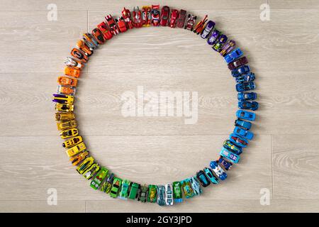 Groupe coloré enfant voiture jouet Hot Wheels dans le cercle de précision sur plancher en bois vue du dessus Banque D'Images
