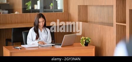 Femme asiatique médecin ou dentiste lisant un document de recherche médicale ou des antécédents médicaux dans le bureau de l'hôpital. Cabinet du médecin concept d'espace de travail Banque D'Images