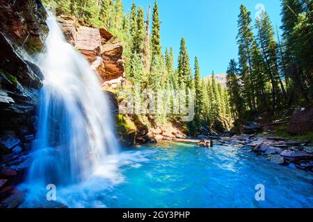 Vue depuis le côté de la cascade bleue pittoresque nichée dans les gorges dans les montagnes entourées de pins Banque D'Images