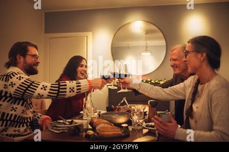 Une bonne famille toasque des verres à vin à la table à manger de la maison.Famille à la table à manger pour le dîner de noël. Banque D'Images