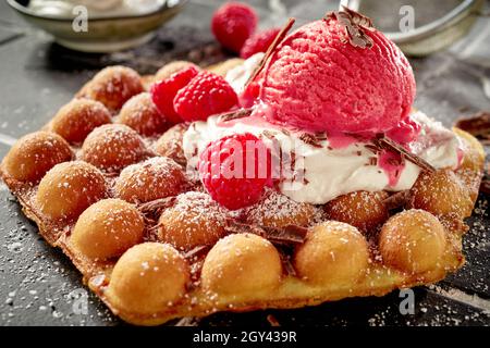 Gaufres traditionnelles aux œufs ou gaufres à la crème glacée savoureuse à la framboise et fruits frais sur crème fouettée pour un délicieux repas gastronomique Banque D'Images