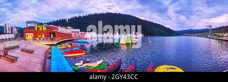 L'agréable promenade en soirée autour de la montagne pittoresque Molodist (Jeunesse) Lac, avec des bateaux touristiques et parc aquatique, Bukovel, Carpates, Ukraine Banque D'Images