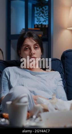 Portrait d'une femme dépressive traumatisée, frustrée et stressée regardant à distance assis seul sur un canapé se sentant émotionnellement instable, solitaire désespéré, vulnérable souffrant d'anxiété, maladie chronique Banque D'Images