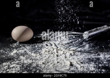 Whisky argenté avec œuf et farine blanche sur un comptoir de cuisine noir, macrophotographie Banque D'Images