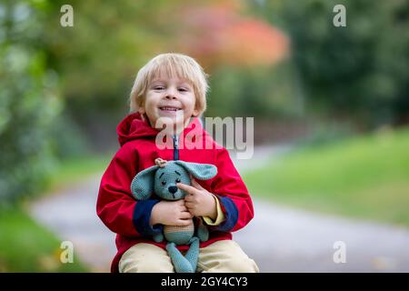 Petit enfant, garçon, jouant avec le jouet tricoté de chien amigurumi dans le parc d'automne, l'heure de l'automne Banque D'Images