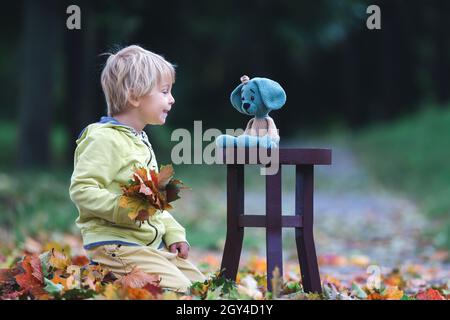 Petit enfant, garçon, jouant avec le jouet tricoté de chien amigurumi dans le parc d'automne, l'heure de l'automne Banque D'Images