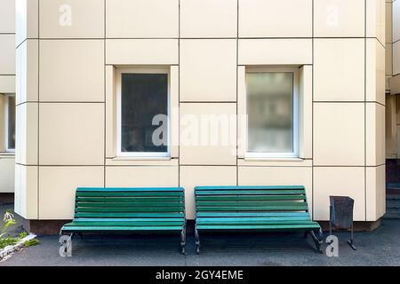 Banc vide contre façade classique avec de grandes fenêtres blanches dans l'arrière-cour du bâtiment.Gros plan.À l'extérieur. Banque D'Images