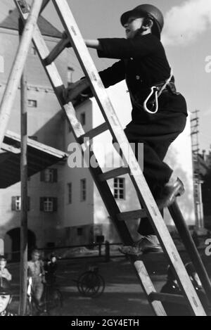 Ein Junge von der Kinderfeuerwehr erklettert bei einer Feuerwehrübung eine Leiter, Deutschland 1930 er Jahre. Un garçon de la pompiers junior est l'escalade sur une échelle au cours d'une formation de pompier, Allemagne 1930. Banque D'Images