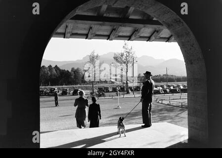 Jägeri, Deutschland, 1930er Jahre.De jeunes femmes se promènent et un gentleman marche son chien en face de la vue panoramique sur les Alpes de Chiemgau, Allemagne des années 1930. Banque D'Images