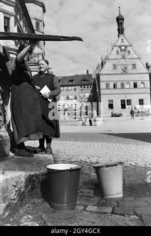 Zwei Frauen verwalten sich während Sie die Wassereimer mit Wasser aus dem Springbrunnen Am Marktplatz vor dem Rathaus und der Ratstrinkstube voll laufen lassen, Rothenburg ob der Tauber, Allemagne Allemagne Années 1930 er Jahre. Deux femmes ayant un chat tandis que le bucktes sont remplissage avec de l'eau de la fontaine sur la place du marché à proximité de la mairie et Ratstrinkstube à Rothenburg ob der Tauber, Allemagne 1930. Banque D'Images