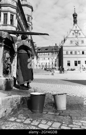 Zwei Frauen verwalten sich während Sie die Wassereimer mit Wasser aus dem Springbrunnen Am Marktplatz vor dem Rathaus und der Ratstrinkstube voll laufen lassen, Rothenburg ob der Tauber, Allemagne Allemagne Années 1930 er Jahre. Deux femmes ayant un chat tandis que le bucktes sont remplissage avec de l'eau de la fontaine sur la place du marché à proximité de la mairie et Ratstrinkstube à Rothenburg ob der Tauber, Allemagne 1930. Banque D'Images