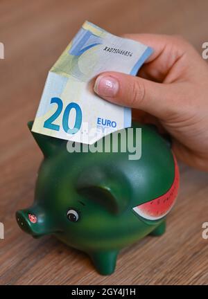 Sieversdorf, Allemagne.05e octobre 2021.ILLUSTRATION: Une fille met une note de 20 euros dans une banque de piggy (coup de feu posé).L'étude Allianz Wealth intitulée « Allianz Global Wealth Report 2021 » est présentée le 07.10.2021.Credit: Patrick Pleul/dpa-Zentralbild/dpa/Alay Live News Banque D'Images