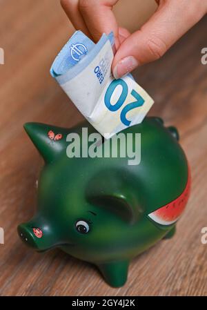 Sieversdorf, Allemagne.05e octobre 2021.ILLUSTRATION: Une fille met une note de 20 euros dans une banque de piggy (coup de feu posé).L'étude Allianz Wealth intitulée « Allianz Global Wealth Report 2021 » est présentée le 07.10.2021.Credit: Patrick Pleul/dpa-Zentralbild/dpa/Alay Live News Banque D'Images