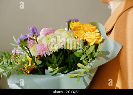 Une femme au pelage beige tient un beau bouquet d'automne dans ses mains.Couche de couleur chameau.Concept de dépersonnalisation.Gros plan. Banque D'Images